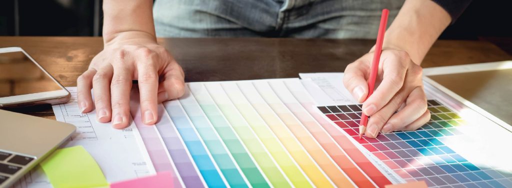 Designer choosing colors from Pantone swatch chart