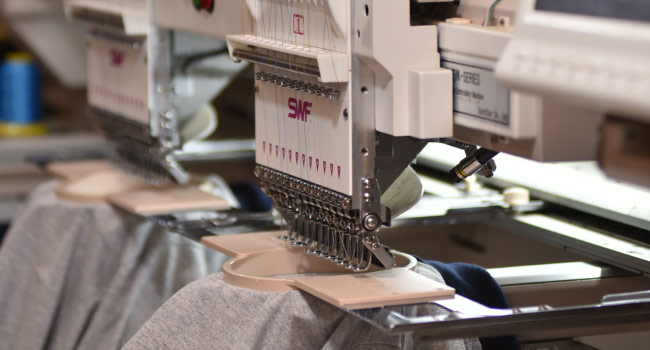 Industrial embroidery machine stitching on gray garment