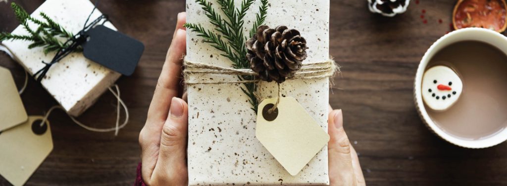 Holiday gift wrapping scene with hot cocoa and pine cones